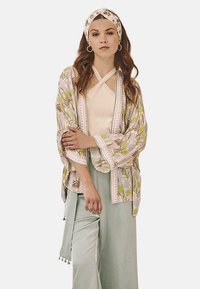 Chaqueta estilo kimono en rosa claro, con patrones florales, combinada con una blusa crema y pantalones de pierna ancha en verde menta, de textura suave.