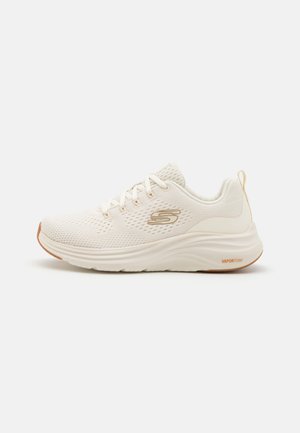 Białe sportowe buty z siateczkową cholewką, teksturowanymi detalami, wiązanym fasonem i amortyzującą podeszwą. Posiadają oznaczenie "VaporFoam" z boku.