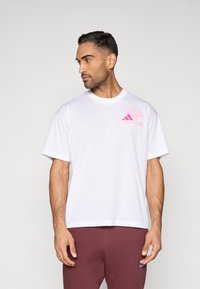 Biele bavlnené tričko s krátkymi rukávmi, na ľavej strane na hrudi s ružovým grafickým logom a klasickým okrúhlym výstrihom.