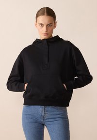 Felpa nera con cappuccio, tasca frontale e collo a mezza zip. Realizzata in tessuto morbido, presenta una vestibilità comoda e polsini a coste.