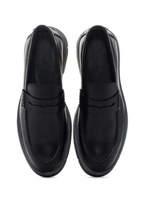 Mocasines de cuero negro con un acabado suave, que presentan un detalle cosido en la parte superior y una suela de goma texturizada para mayor agarre.