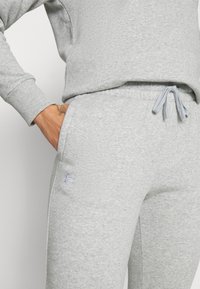Under Armour RIVAL FLEECE - Pantaloni sportivi - mod gray light heather/white