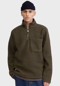 Fleece-Pullover in dunkelolivgrün mit einem Viertel-Reißverschluss vorne und einer Brusttasche. Ausgestattet mit einem weichen, strukturierten Stoff und einer lässigen Passform.