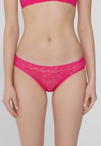 Rosa Spitzenunterwäsche mit einem zarten Blumenmuster, glattem Bund und Kanten. Das Material ist durchsichtig und leicht.
