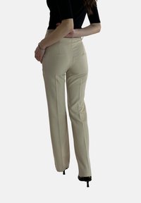 Beige op maat gemaakte broek met een gladde textuur, hoge taille en rechte pijpen, voorzien van achterzakken en een traditionele uitstraling.