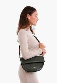 Tmavě zelená kožená crossbody taška s hladkým povrchem, zakřiveným tvarem a zlatým logem. Obsahuje nastavitelný popruh.