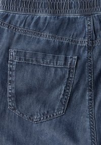 Džínové šortky s elastickým pasem, vybavené jednou zadní kapsou a tmavě modrou, texturovanou tkaninou s viditelnými švy.