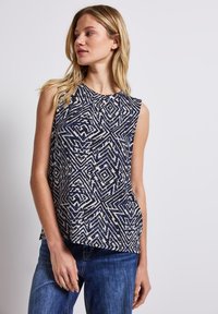 Top senza maniche navy e crema con un motivo geometrico e scollo a barca. Realizzato in tessuto leggero con una vestibilità rilassata.