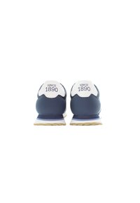Navyblå sneakers med vita detaljer, som har en vadderad häl och texten "SINCE 1890". Texturerad gummisul och strömlinjeformad design.