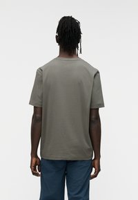 Λαδί κοντομάνικο T-shirt με στρογγυλή λαιμόκοψη, φτιαγμένο από μαλακό ύφασμα, με απαλή υφή και άνετη εφαρμογή, φαίνεται από πίσω.