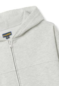 Sudadera con capucha gris claro con cremallera, que presenta un forro interior texturizado, capucha ajustable y costuras frontales simples. Etiqueta visible en el interior del cuello.