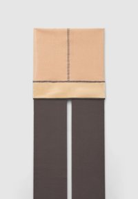 Sciarpa piegata beige e crema con cuciture visibili abbinata a un paio di pantaloni dritti grigi scuri su uno sfondo chiaro.