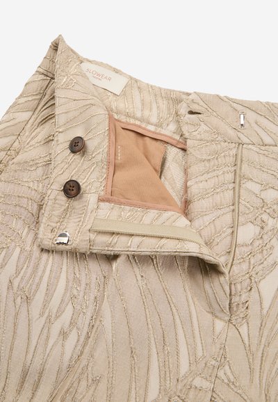 Pantaloni beige con texture e dettagli ricamati, dotati di due bottoni marroni, una cerniera e una chiusura con gancio e occhiello.