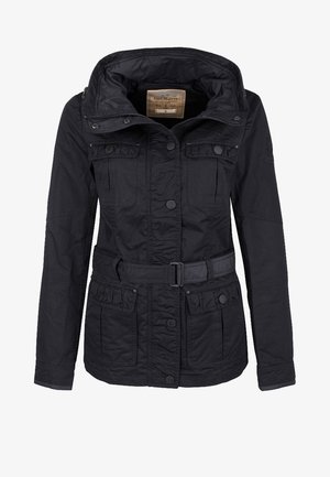 Veste noire à ceinture avec col montant, poches boutonnées sur la poitrine et les hanches, manches longues, et fermeture à pressions sur le devant.