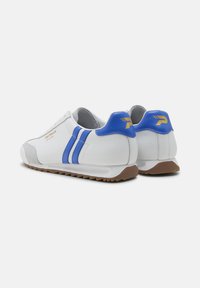 Zapatillas blancas con rayas azules, acentos de ante gris y suelas de goma marrón. Presentan un logo dorado en el talón y una parte superior texturizada.