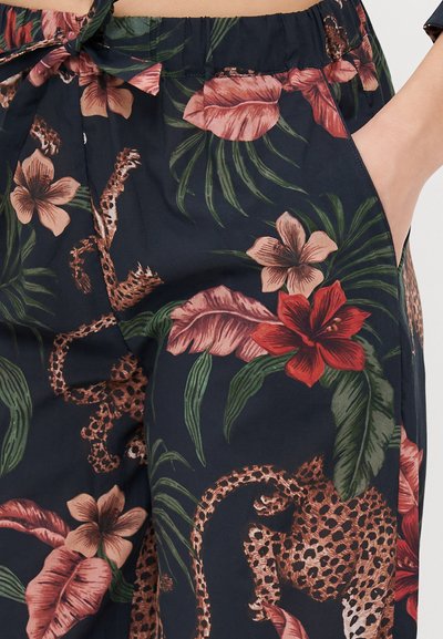 Calças florais com um fundo azul-marinho, flores vibrantes em rosa e vermelho, folhas verdes e um padrão de estampado de leopardo; cintura elástica com um cordão.