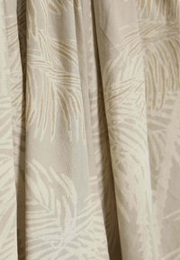 Tkanina o jasnobeżowym tle z delikatnym wzorem liści palmy w kolorze kremowym i miękkim taupe, prezentująca gładką, teksturowaną powierzchnię.