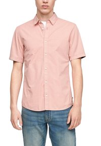 Košile s krátkým rukávem na knoflíky ze světlě růžové bavlny. Má límec, knoflíky vpředu a zaoblený lem. Nošena s světle modrými džínami.