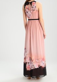 Maxikleid aus zartem pinken Stoff, mit einem Blumendruck am Saum, schwarzen Akzenten am Ausschnitt und einer taillierten Passform mit Falten.