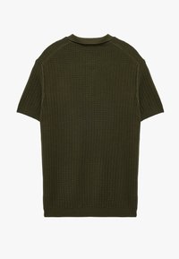 Olivgrön kortärmad tröja med ribbad textur, rundad krage och öppen fåll; har detaljer vid axelsömmar och en avslappnad passform.
