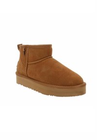 Stivale alla caviglia in suede marrone con punta arrotondata, texture morbida, soletta imbottita e cuciture minime. Presenta una chiusura a zip sul lato.