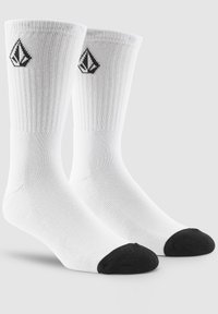 Weiße Baumwollsocken mit gerippten Bündchen, schwarzen verstärkten Zehenkappen und einem kleinen schwarzen Logo an der Seite. Standard Crew-Länge Design.