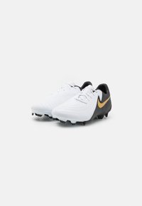 Vit och svarta fotbollsskor med texturerad ovandel, böjd silhuett, spetsig tå och svarta dobbar. Guld Nike-logga på den laterala sidan.