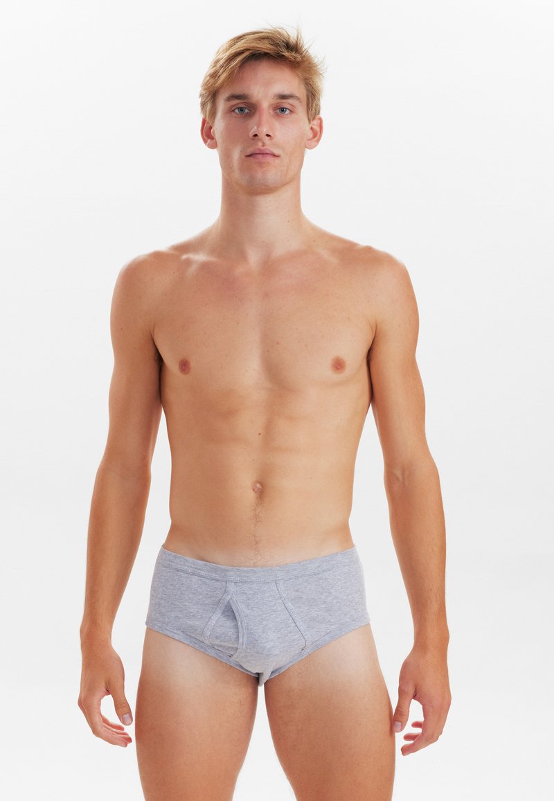 Grå bomulds underbukser med lavtalje og forlommer, præsenteret på en bare torso mod en hvid baggrund.