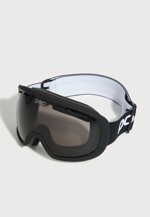 Lunettes de ski noires avec verres teintés et sangle noire et blanche réglable avec la marque "poc" sur un fond uni.