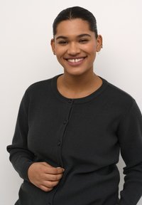 Dunkelgraue gerippte Strickjacke mit Rundhalsausschnitt, vorderer Knopfschließe und langen Ärmeln. Glatte Textur und schlichtes Design.