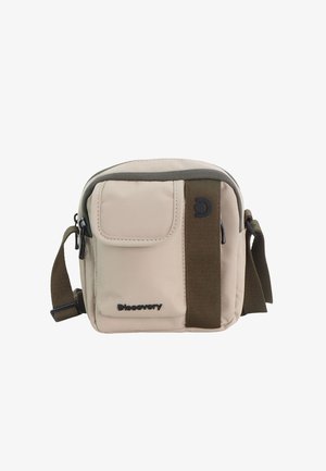 Beige kompakte Umhängetasche mit vorderer Klappentasche, braunen Trägerdetails, verstellbarem Schultergurt und "Discovery"-Logo auf der Vorderseite.