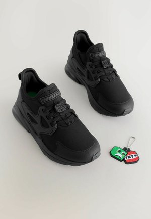 Mustat lenkkarit, joissa on teksturoitu kangaspäällinen, jossa on voimakas nauhoitusjärjestelmä, pyöreä kärki ja irrotettava avainketju.