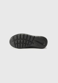 Semelle en caoutchouc noir de baskets avec un motif en grille pour une traction optimale et un logo de marque voyant, conçue pour la durabilité et l'adhérence.