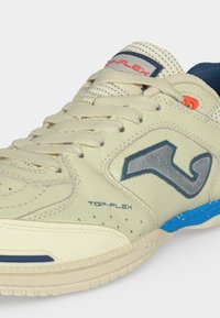 Αθλητικό παπούτσι σε εκρού χρώμα με κορδόνια μπροστά, γκρι λογότυπο στο πλάι, μπλε λεπτομέρειες και το κείμενο «TOP-FLEX» κοντά στη σόλα.