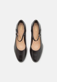 Scarpe in pelle nera con punta arrotondata e cinturino alla Mary Jane, dotate di una fibbia metallica e una soletta leggera e imbottita.