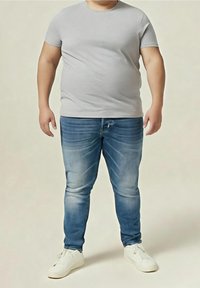 Camiseta de algodón gris, vaqueros de mezclilla azul con desgaste y zapatillas blancas. Diseño de ajuste ajustado con un cuello redondo clásico.