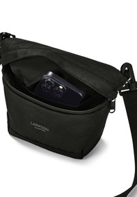 Svart crossbody-väska med en ficka framtill som har dragkedja, innehållande en telefon. Tillverkad av texturerat tyg, med justerbar rem och logodetalj.