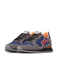 Ein Paar blaue und graue Sneaker mit schwarzen Schnürsenkeln, orangefarbenem Innenfutter, rotem Seitenlogo und weißem Etikett auf der Zunge, schräg auf einem weißen Hintergrund dargestellt.