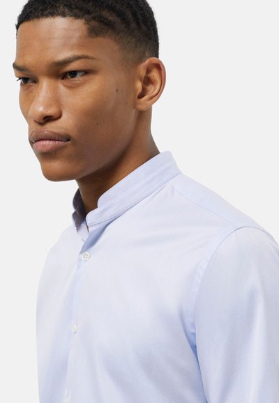 Camicia azzurra chiara con design a bottoni e texture liscia, dotata di colletto alla mandarino e silhouette aderente.