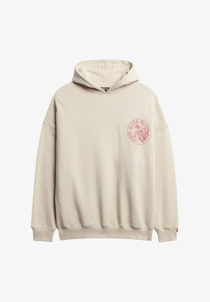 Beige oversized hoodie van zacht materiaal met een voorop gedrukt grafisch logo in het roze, een kangoeroezak en ribgebreide boorden en zoom.