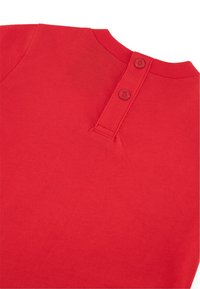 Prenda de algodón roja con escote redondeado, que presenta dos botones a juego en la parte posterior y una textura suave y lisa.