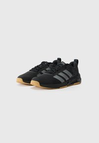 Black athletic shoes with a mesh upper, featuring three grey stripes, a textured black midsole, and a gum rubber outsole.