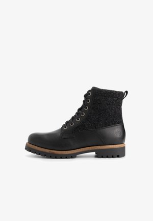 Zwarte leren enkelboot met een getextureerde zwarte wollen bovenkant, ronde neus en metalen oogjes. Voorzien van een bruine rubberen zool en hak.