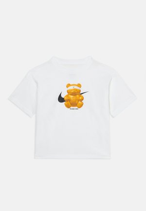 Camiseta blanca con un gráfico central de un oso naranja que lleva una cinta de Nike blanca en la cabeza, logo de Nike detrás y el texto "the bear-y best".
