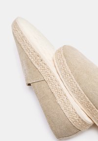 Beige Espadrille mit einem Obermaterial aus Leinen, geflochtenem Jutemittelsohle und einer flachen, strukturierten Gummisohle. Merkmale sind minimalistisches Design und Nähakzente.
