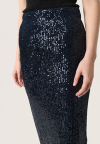 Fustă de sequins bleumarin cu o siluetă ajustată, având o suprafață texturată și un brâu elastic, care reflectă lumina pentru un efect strălucitor.