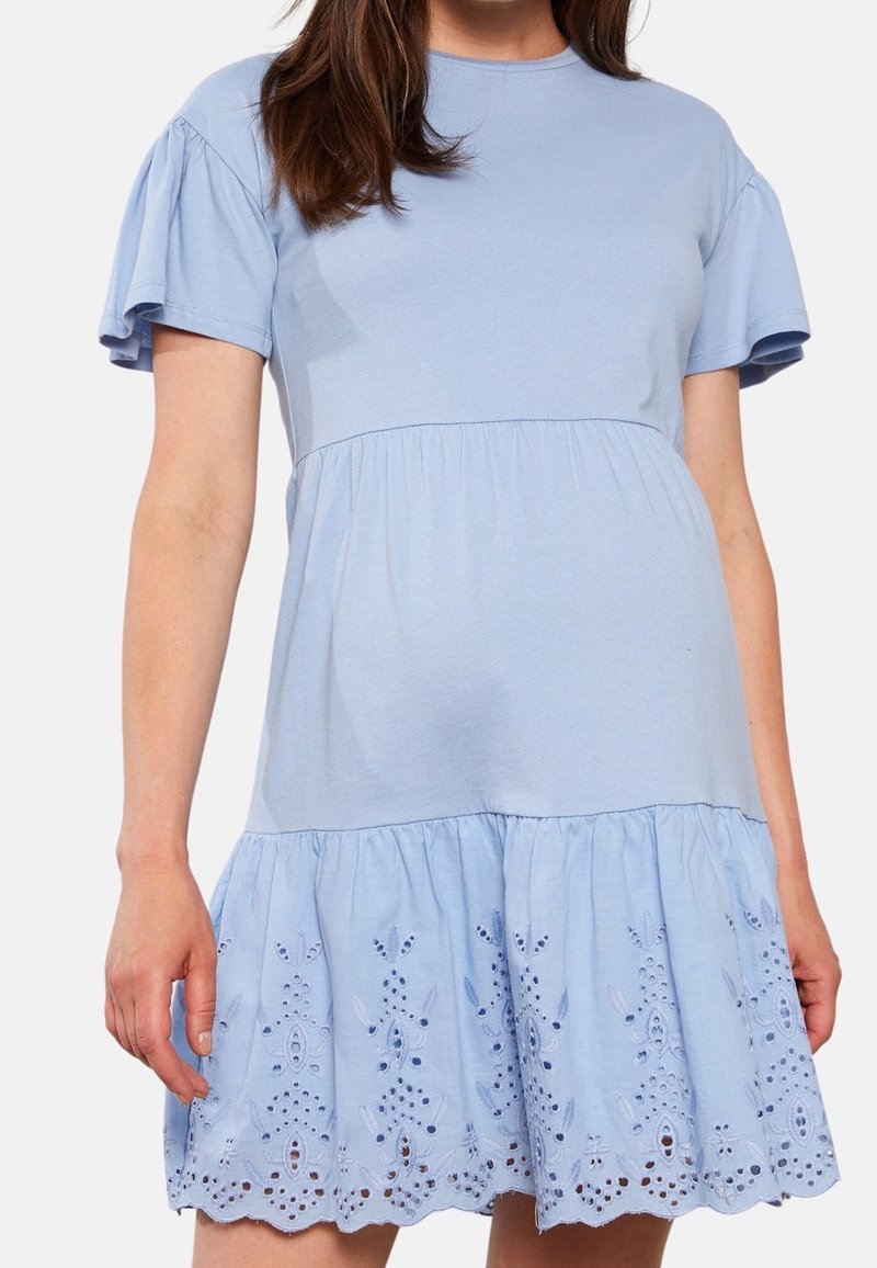 Vaaleansininen puuvillamekko, jossa on lyhyet röyhelöhihoja, tiivistetty vartalo ja kerroksellinen hame, jossa on brodeerattuja kukkakuvioita helman reunassa.