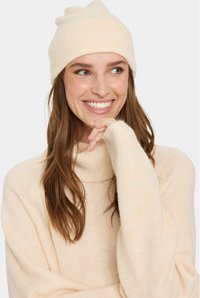 Gorro de punto acanalado color crema y suéter suave y ligero con cuello tipo mock. Presenta un corte relajado y una textura sutil.