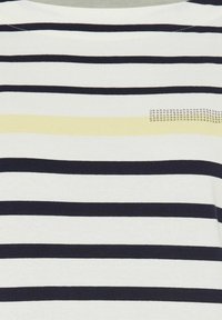 Gestreiftes kurzärmliges Oberteil mit navyblauen und weißen horizontalen Streifen, das eine gelbe Akzentlinie und metallische Nietenapplikationen auf der Brust aufweist.