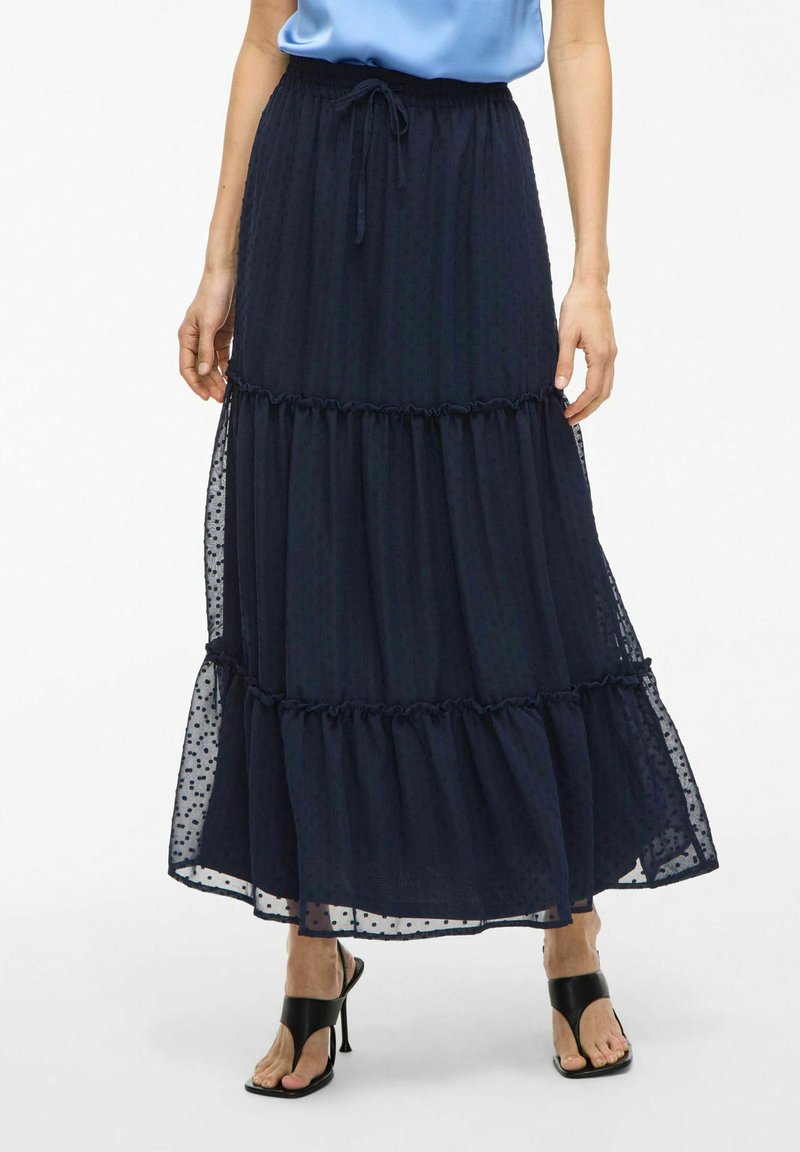 Gonna maxi a strati blu navy realizzata in tessuto leggero con una trama a pois, dotata di una vita con cordoncino e bordi arricciati.